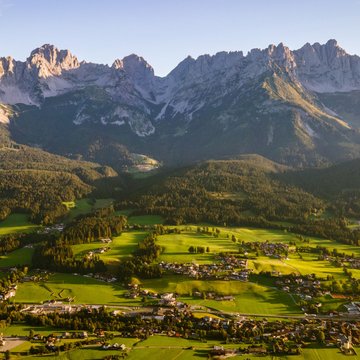 Urlaub in Söll mit Kindern oder als Pärchen Blick auf grüne Landschaft und Bergkette im Gegenlicht