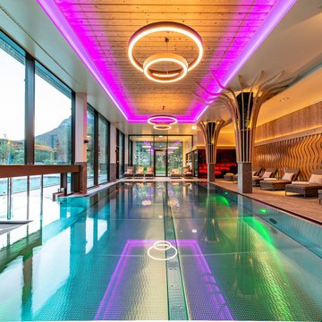 Urlaub in Söll mit Kindern oder als Pärchen Moderner Innenpool mit Lounge-Stühlen und neonbeleuchtetem Deckenrahmen