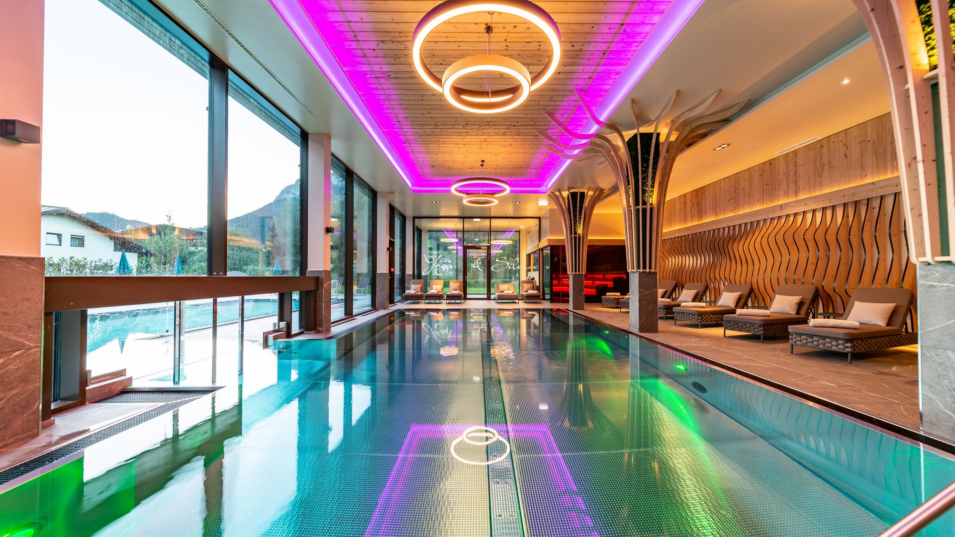 Der Postwirt: Hotel mit Infinitypool in Tirol Moderner Innenpool mit Lounge-Stühlen und neonbeleuchtetem Deckenrahmen