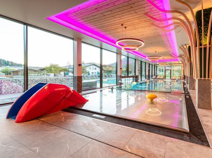 Der Postwirt: Hotel mit Infinitypool in Tirol Kinderbecken mit Rutsche und moderner Beleuchtung in einem Hallenbad