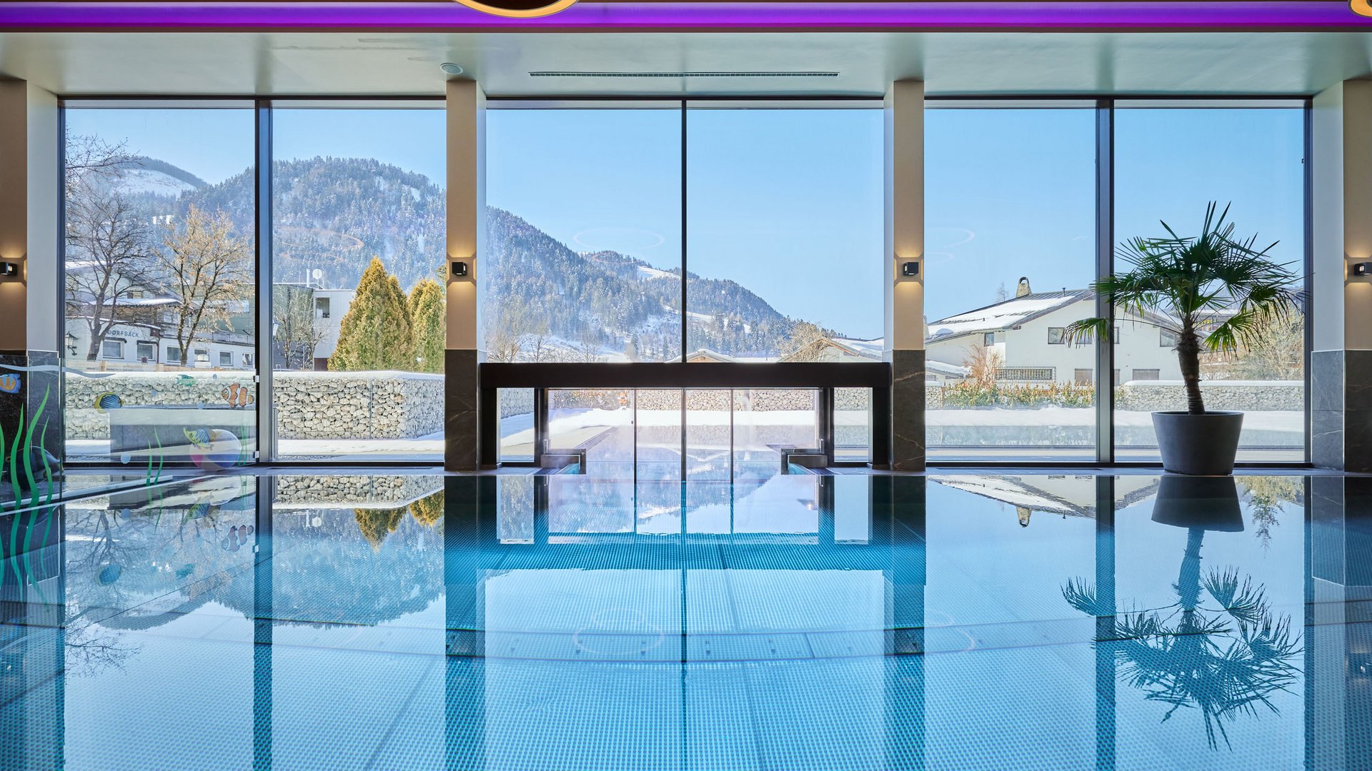 Hotel in Söll am Wilden Kaiser: der Postwirt Innenpool mit großen Fenstern und Bergblick im Winter