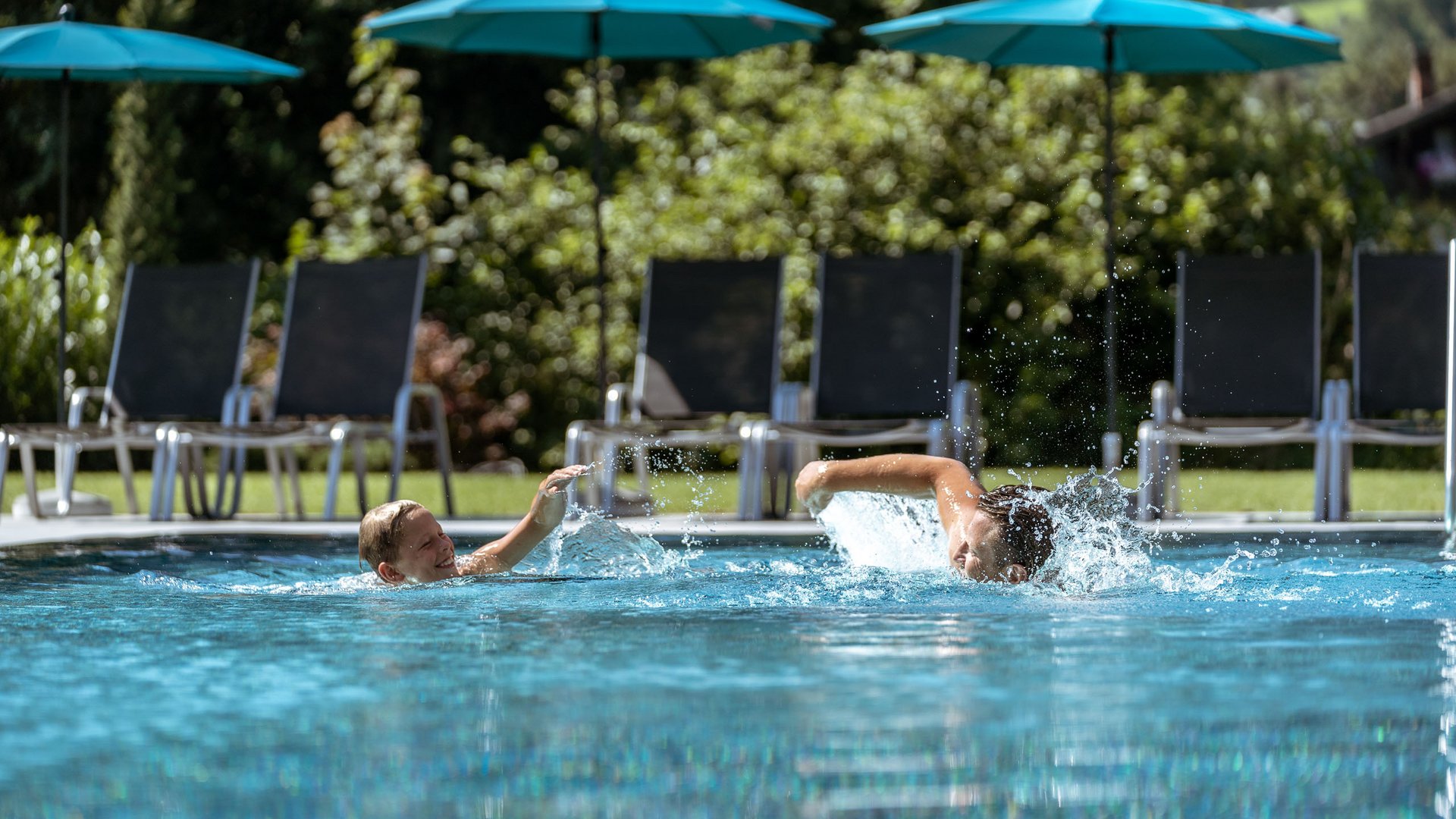 Familienhotel in Söll: der Postwirt Zwei Kinder spielen und schwimmen mit Wasserplanschen im Freibad