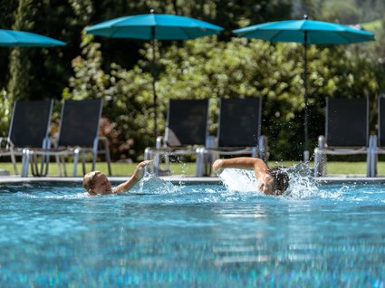 Der Postwirt: Hotel mit Infinitypool in Tirol Zwei Kinder spielen und schwimmen mit Wasserplanschen im Freibad