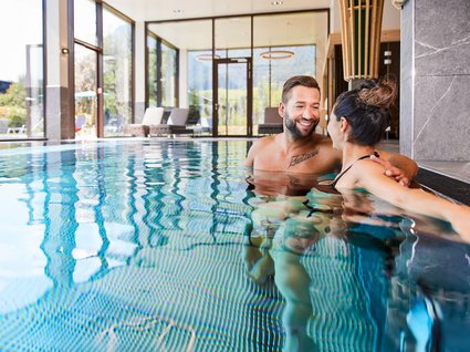 Der Postwirt: Hotel mit Infinitypool in Tirol Paar entspannt im beheizten Hallenbad mit großen Fenstern und Bergsicht