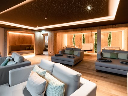 Sie suchen ein Wellnesshotel in Tirol für adults only? Moderner Ruheraum mit Sofas, Holzwänden und sanfter Beleuchtung
