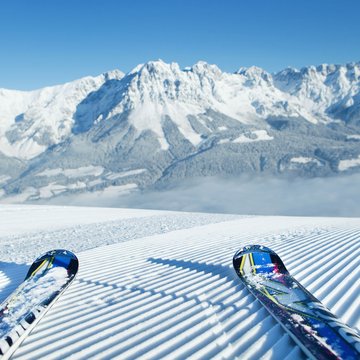 Urlaub in Söll mit Kindern oder als Pärchen Zwei Skier auf frisch präparierter Piste mit Bergpanorama im Hintergrund