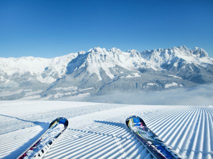 Winter in Söll: das Skigebiet SkiWelt Wilder Kaiser Zwei Skier auf frisch präparierter Piste mit Bergpanorama im Hintergrund
