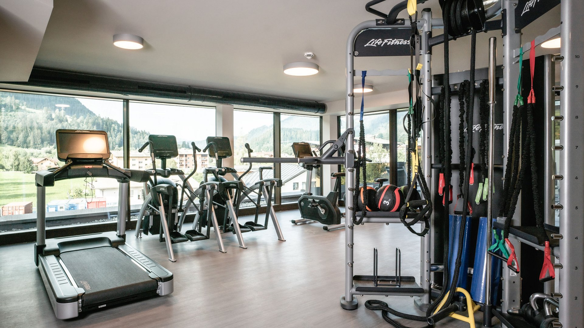 Sie suchen ein Hotel mit Fitnessstudio in Österreich? Moderner Fitnessraum mit Laufband, Trainingsgeräten und großer Fensterfront