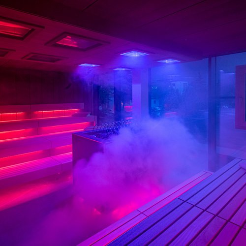 Yoga und Wanderungen in Söll: Emmas Aktivprogramm Moderne Sauna mit roter und blauer Beleuchtung und Dampf