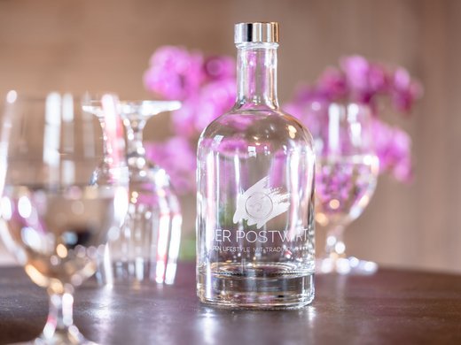 Unser Hotel in Söll/Österreich: eine spannende Geschichte Klare Glasflasche mit Wasser auf Tisch mit Weingläsern und rosa Blumen im Hintergrund