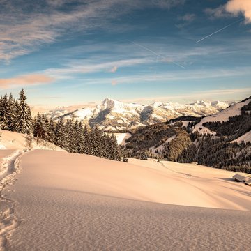 Urlaub in Söll mit Kindern oder als Pärchen Verschneite Alpenlandschaft mit Bäumen, Bergen und blauem Himmel