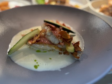 Kulinarische Verführungen in unserem Hotel in Söll/Tirol Kunstvoll angerichtete Gourmet-Garnelen mit Sauce und Gurkenscheiben in einem grauen Teller