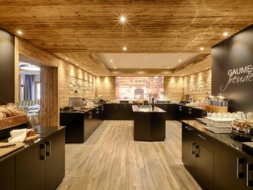 Day Spa in Söll: Kurzurlaub in Tirol Moderne Frühstückstheke mit Brot und Getränken in warm beleuchtetem Raum