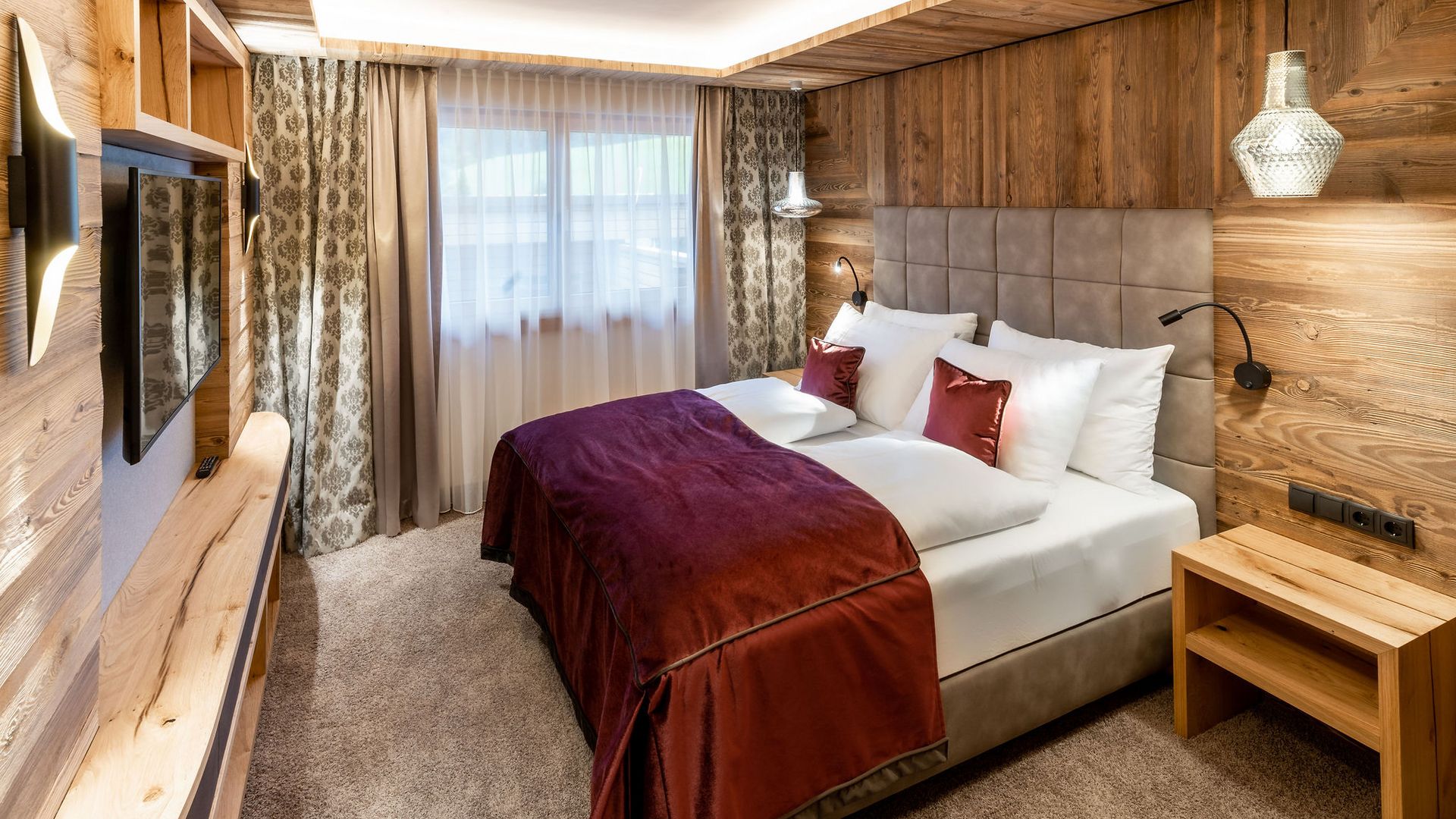 Hotel in Söll am Wilden Kaiser: der Postwirt Gemütliches Hotelzimmer mit Doppelbett, Holzwänden und lila Bettdecke