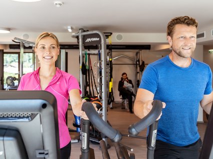 Sie suchen ein Hotel mit Fitnessstudio in Österreich? Frau und Mann trainieren gemeinsam auf Crosstrainern im Fitnessstudio