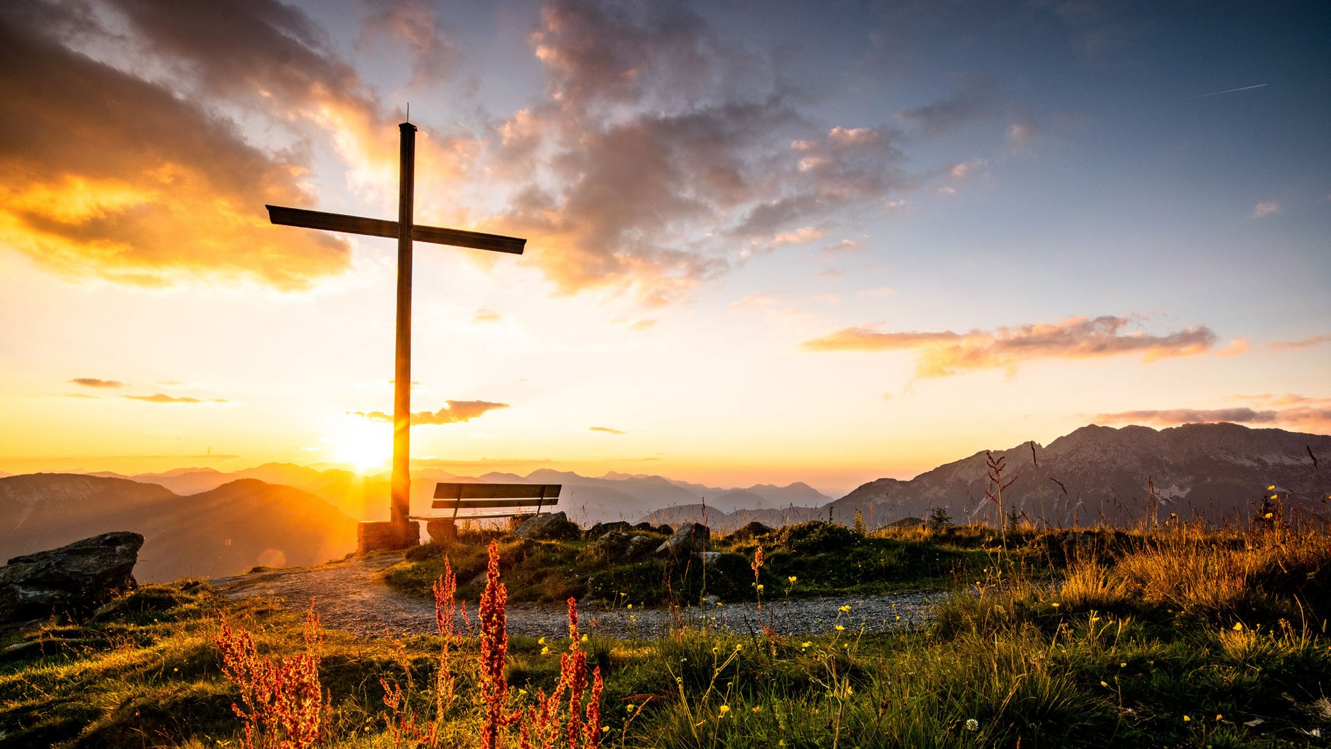 Sommer am Wilden Kaiser: Wandern und mehr Holzkreuz und Bank auf Berg mit Sonnenuntergang und Bergen im Hintergrund