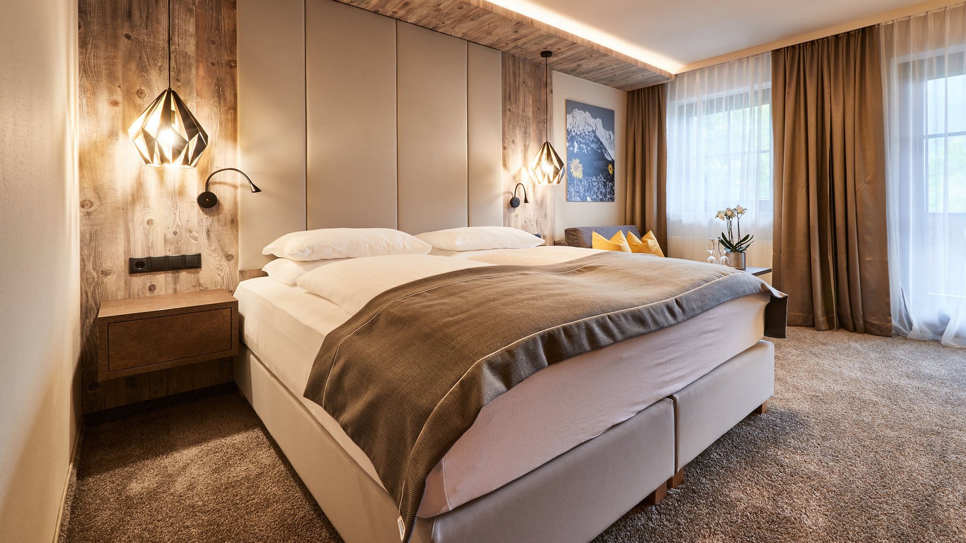 Hotel in Söll am Wilden Kaiser: der Postwirt Modernes Schlafzimmer mit Doppelbett, Holzwand und warmem Licht