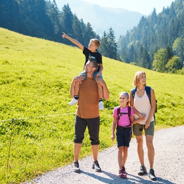 Urlaub in Söll mit Kindern oder als Pärchen Familie wandert auf einem Weg in den Bergen an sonnigem Tag