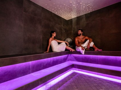 Dampfbad im Wellnessbereich mit stimmungsvoller Beleuchtung Paar entspannt sich in einer Sauna mit lila Beleuchtung