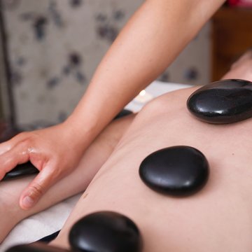 Urlaub in Söll mit Kindern oder als Pärchen Person erhält Hot-Stone-Massage mit Steinen auf dem Rücken und Arm-Massage