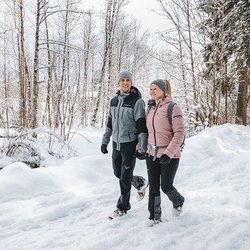 Urlaub in Söll mit Kindern oder als Pärchen Paar wandert im Schnee bei winterlichem Waldspaziergang