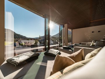 Day Spa in Söll: Kurzurlaub in Tirol Sonnenlicht fällt durch große Fenster in einen modernen, hellen Wohnraum mit Sitzgelegenheiten