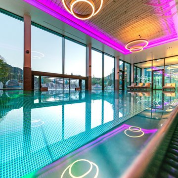 Der Postwirt: Hotel mit Infinitypool in Tirol Modernes Hallenbad mit LED-Beleuchtung und großen Panoramafenstern mit Bergblick