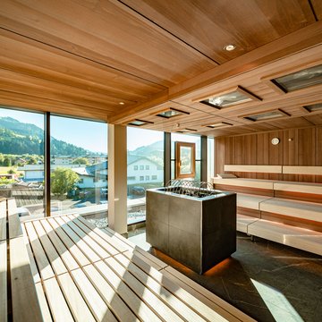 Urlaub in Söll mit Kindern oder als Pärchen Moderner Sauna-Innenraum mit Holzverkleidung und Bergblick durch große Fenster