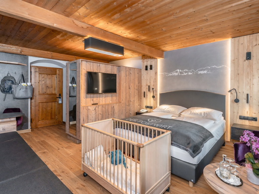 Hochwertige Ausstattung im Familienhotel am Wilden Kaiser Modernes Hotelzimmer mit Holzeinrichtung, Doppelbett und Babybett