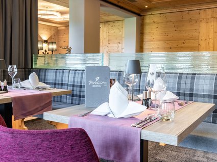 Ihre Traumtage im Postwirt Söll Eleganter gedeckter Tisch in modernem Restaurant mit karierten Sitzbänken