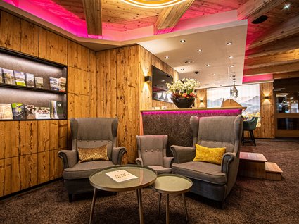Kulinarische Verführungen in unserem Hotel in Söll/Tirol Gemütliche Hotellobby mit Holzverkleidung und modernen Sitzmöbeln