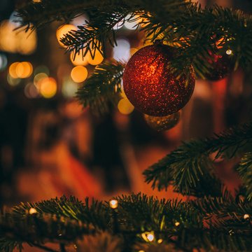 Urlaub in Söll mit Kindern oder als Pärchen Roter Weihnachtsbaumschmuck an Tannenzweig mit verschwommenem Lichterhintergrund